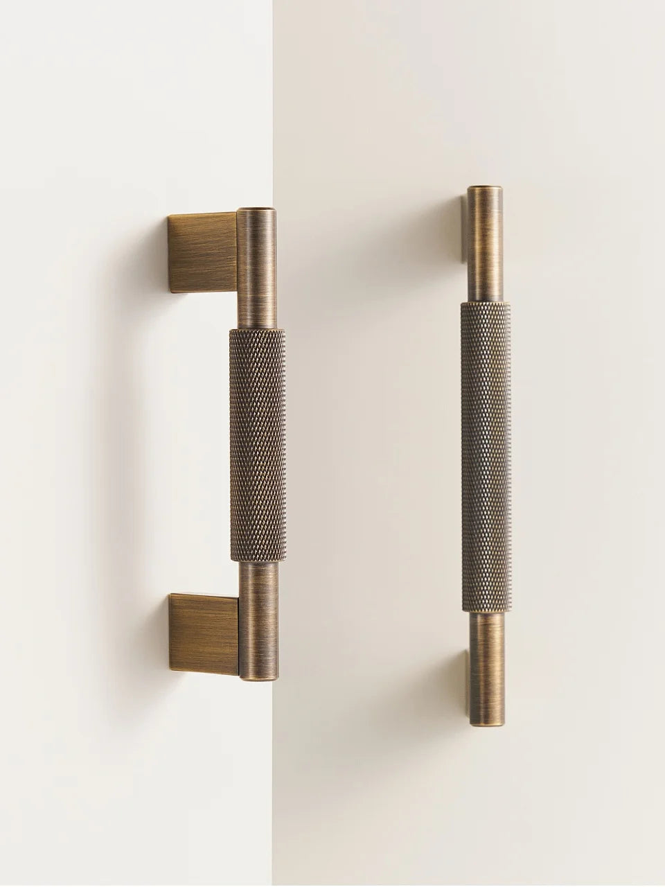 Pair of brass cross knurled door handles on a white background.