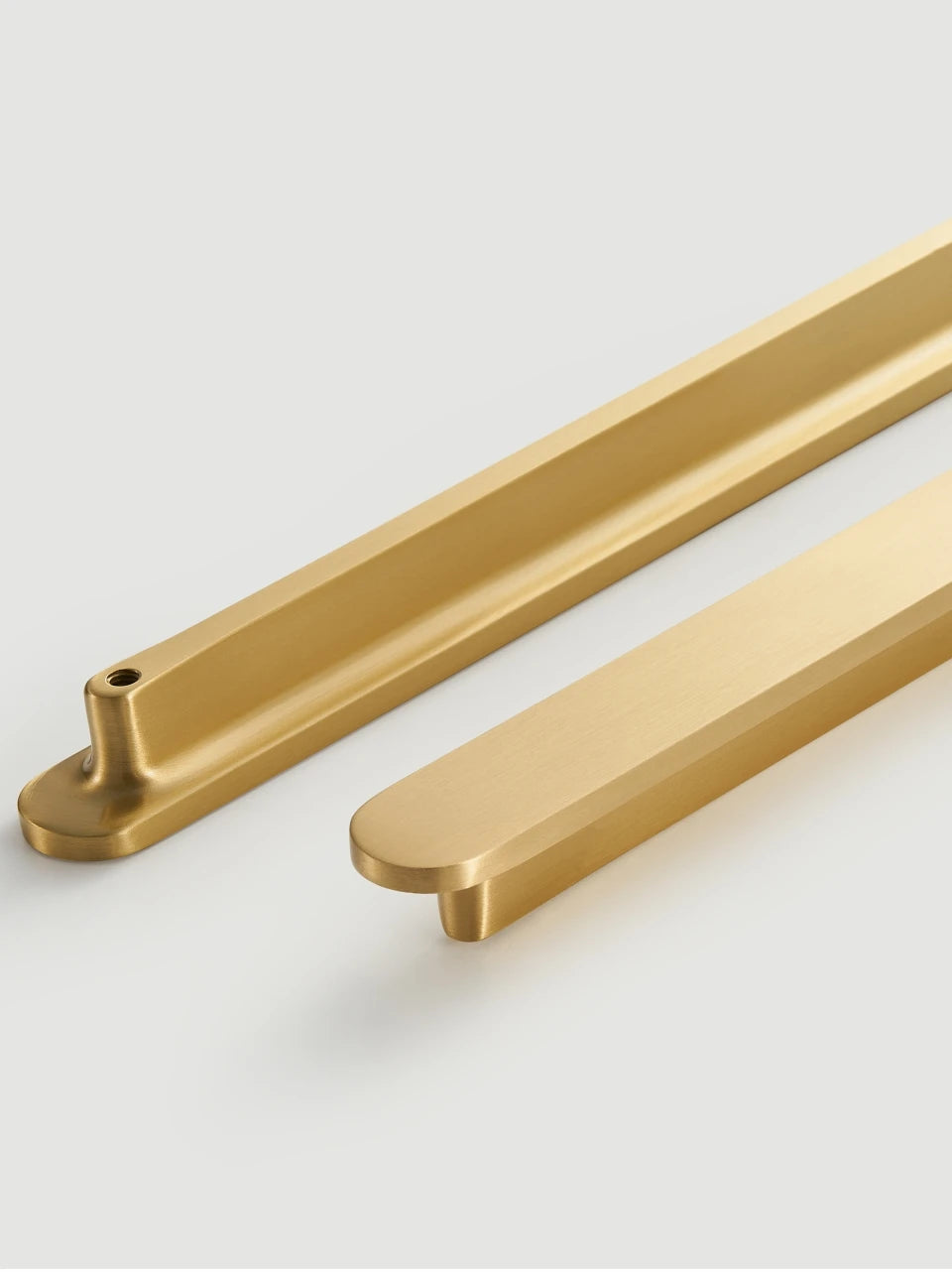Pair of gold brass circular-end handles on a light grey background.