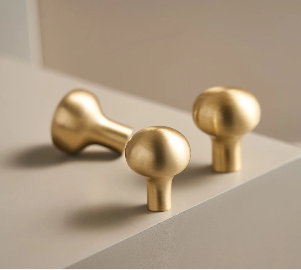 Three gold door handles on a beige surface