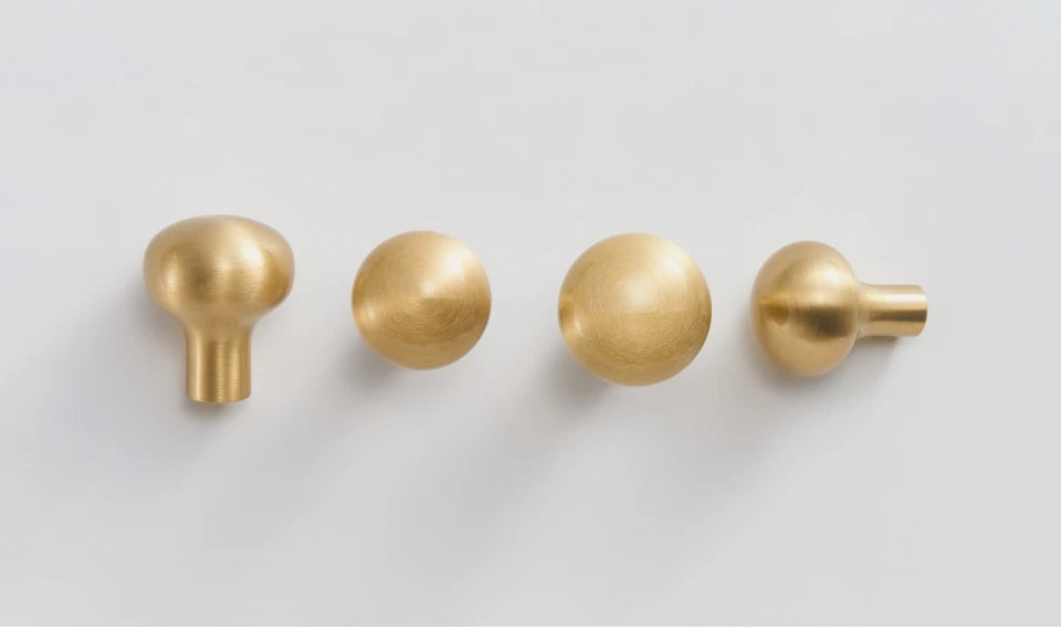 Four gold cabinet knobs on a light gray background