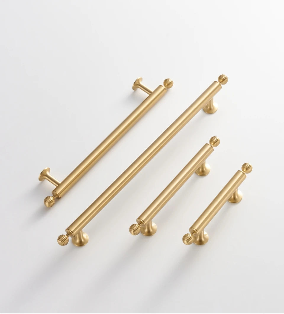 Set of French luxury brass gold pulls on a light gray background.