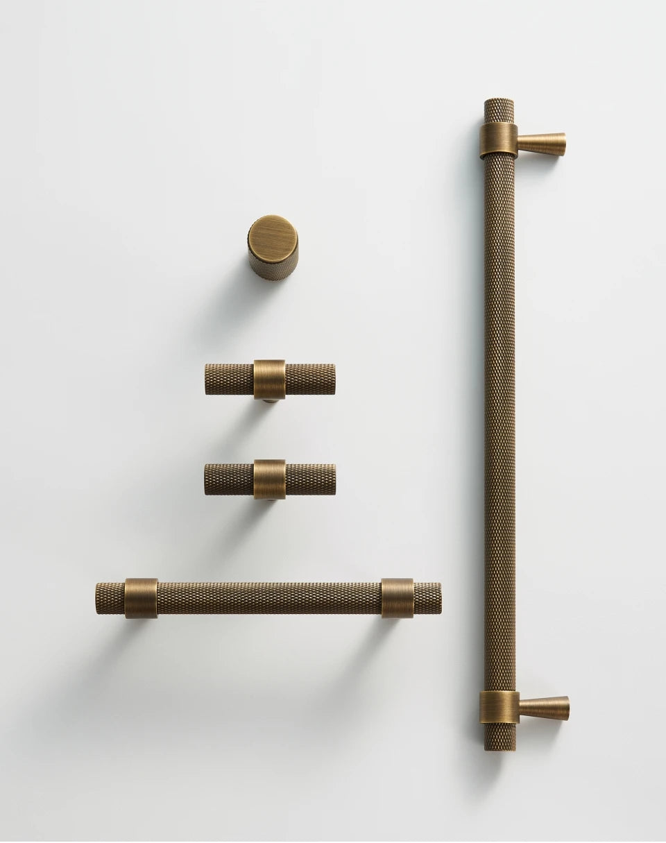 Set of bronze door handles, knobs and t-bars on a neutral background.