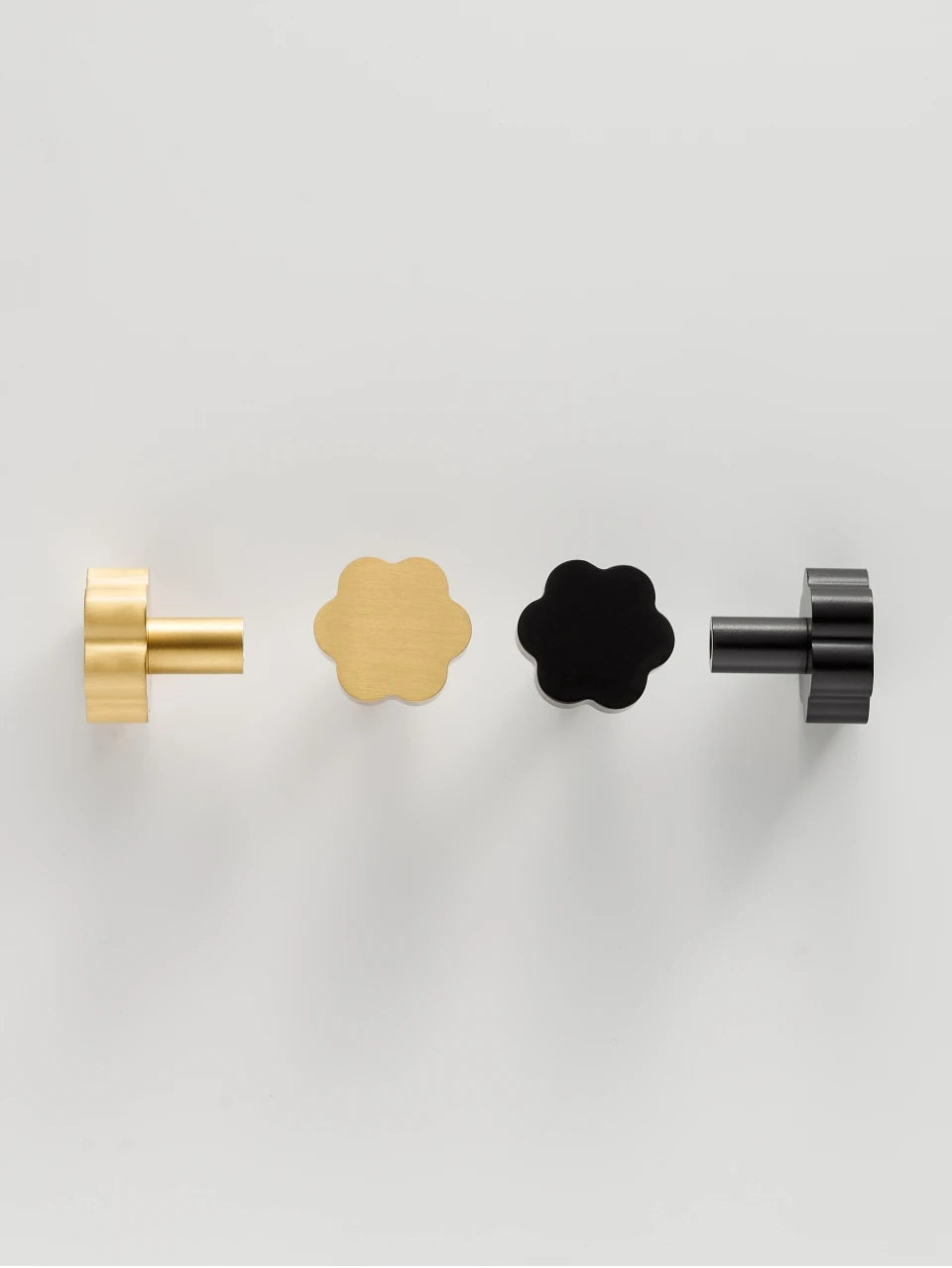 Set of four flower cabinet knobs in gold and black on a light grey background
