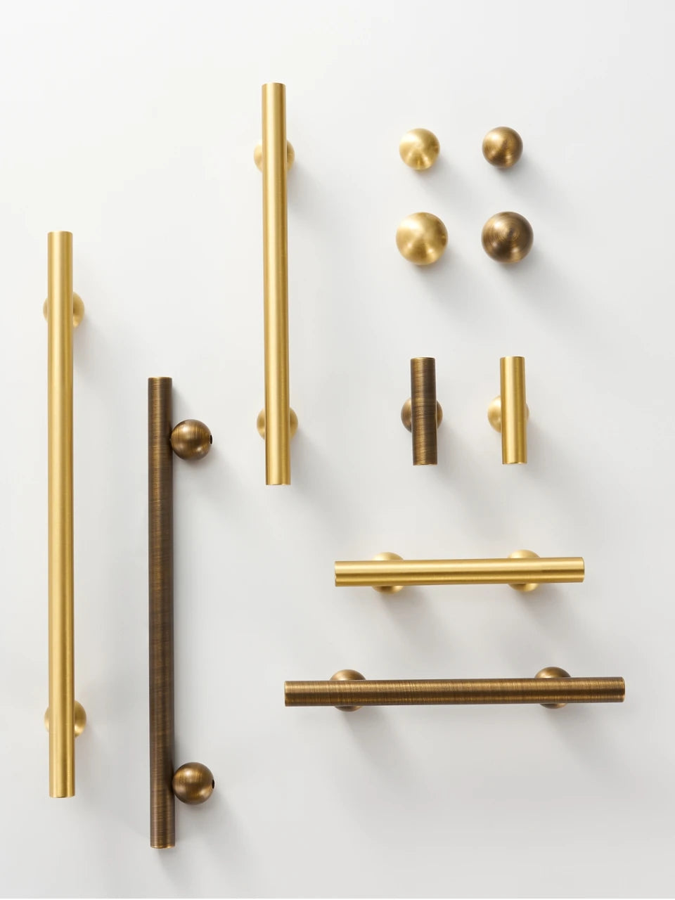 Collection of gold and antique brass round ball handles, t-bars and knobs on a white background.