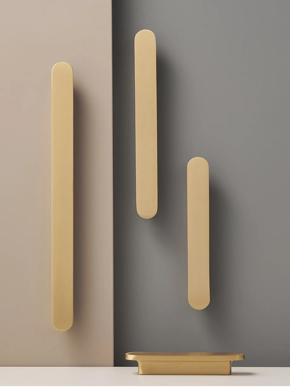 Set of gold brass circular-end handles on a beige and grey background.