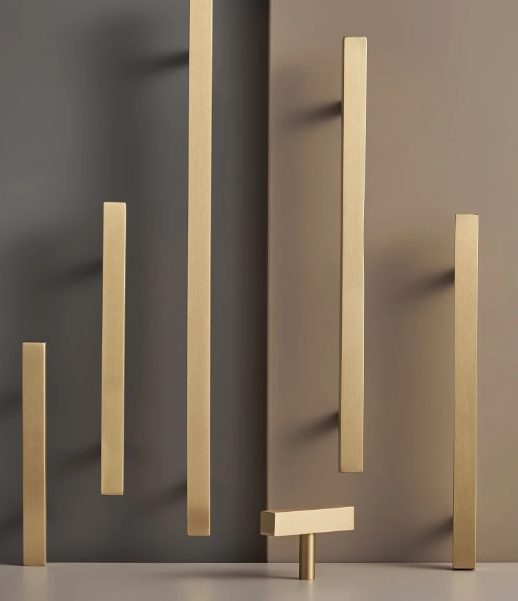 Set of gold brass square handles and t-bar on a beige and grey background.
