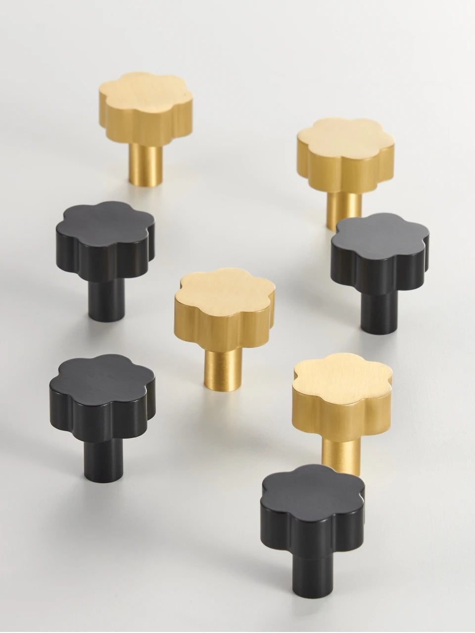 Set of black and gold flower cabinet knobs on a light grey background.