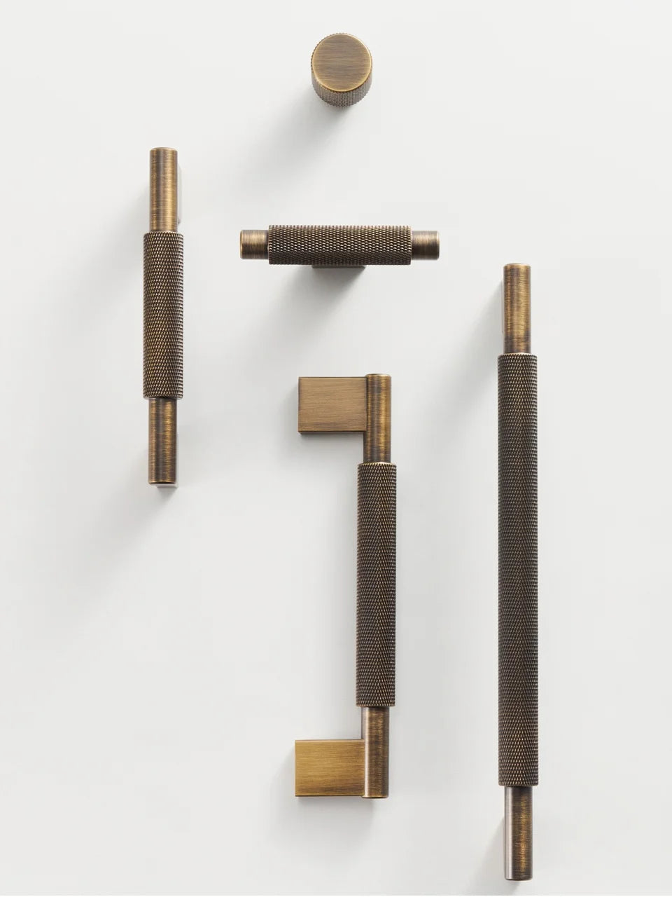 Set of solid brass cross knurled door handles, T-Bar, pull and knob on a white background