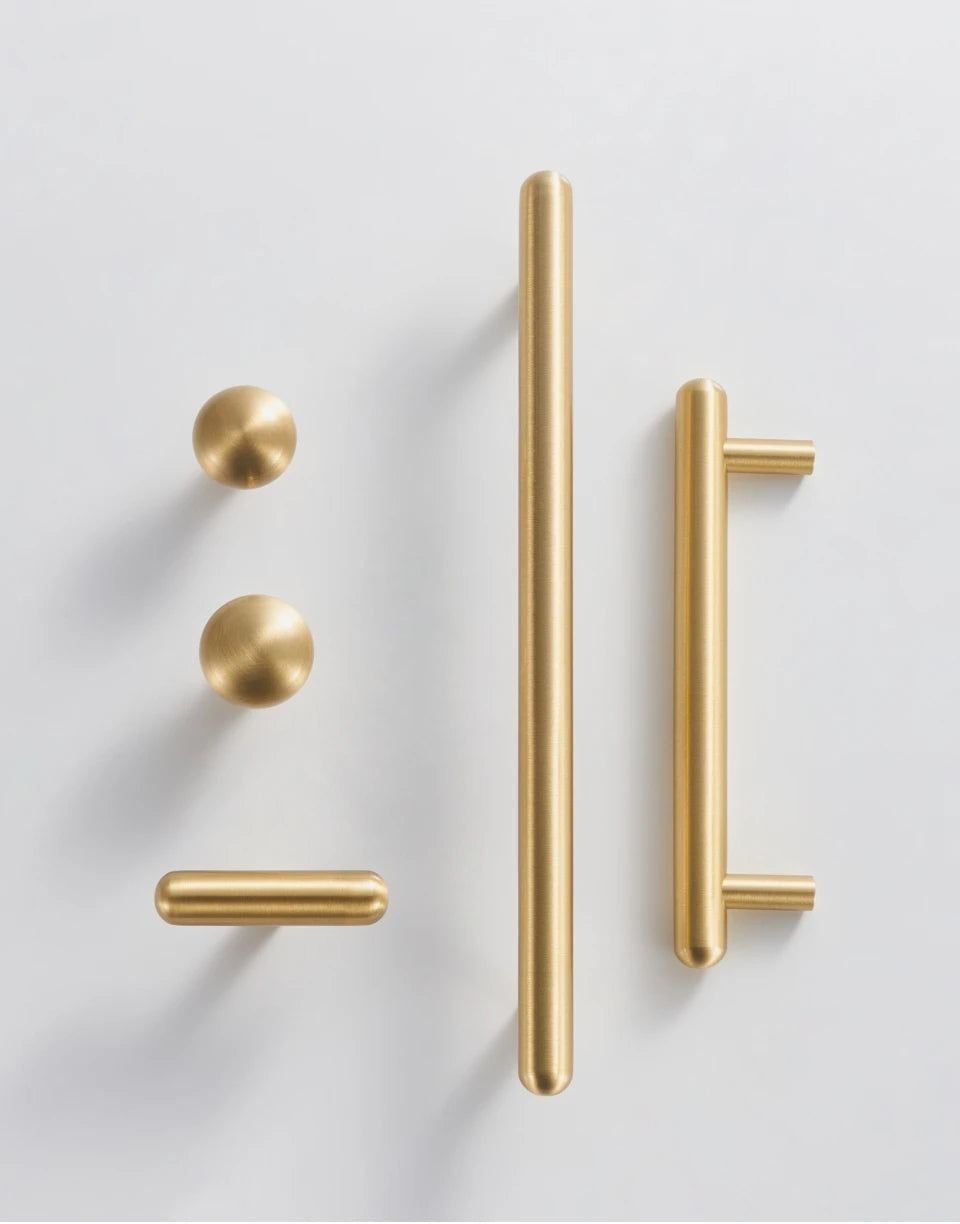 Set of solid brass smooth gold cabinet handles, t-bar and knobs on white background.