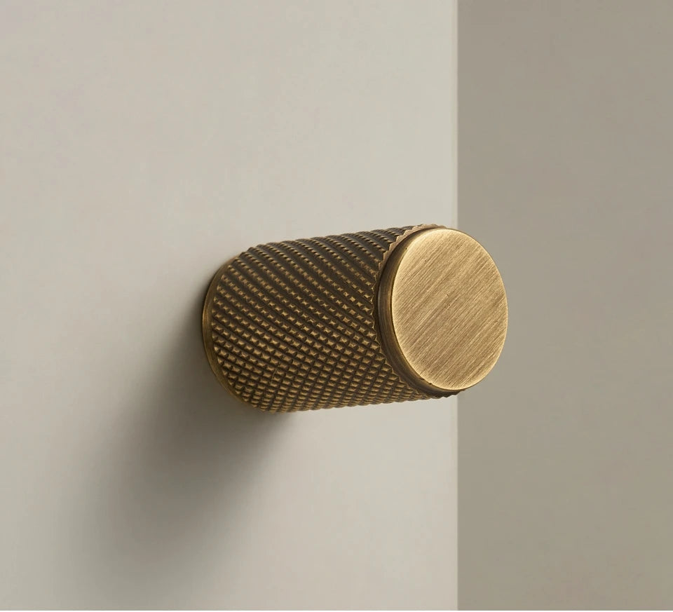 Brass cabinet knob on a neutral, beige background.