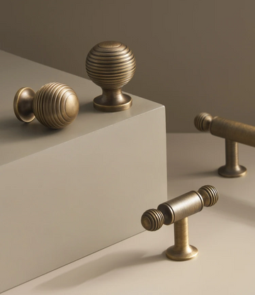 Solid brass antique ball cabinet knobs and t-bar on a neutral and beige background.