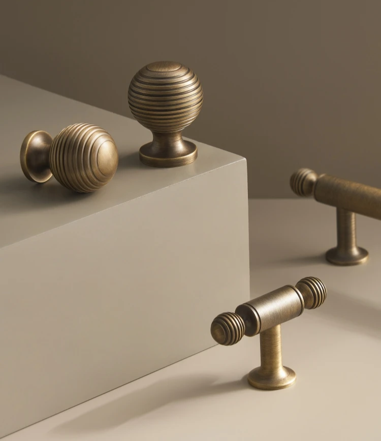 Solid brass antique ball cabinet knobs and t-bar on a neutral and beige background.