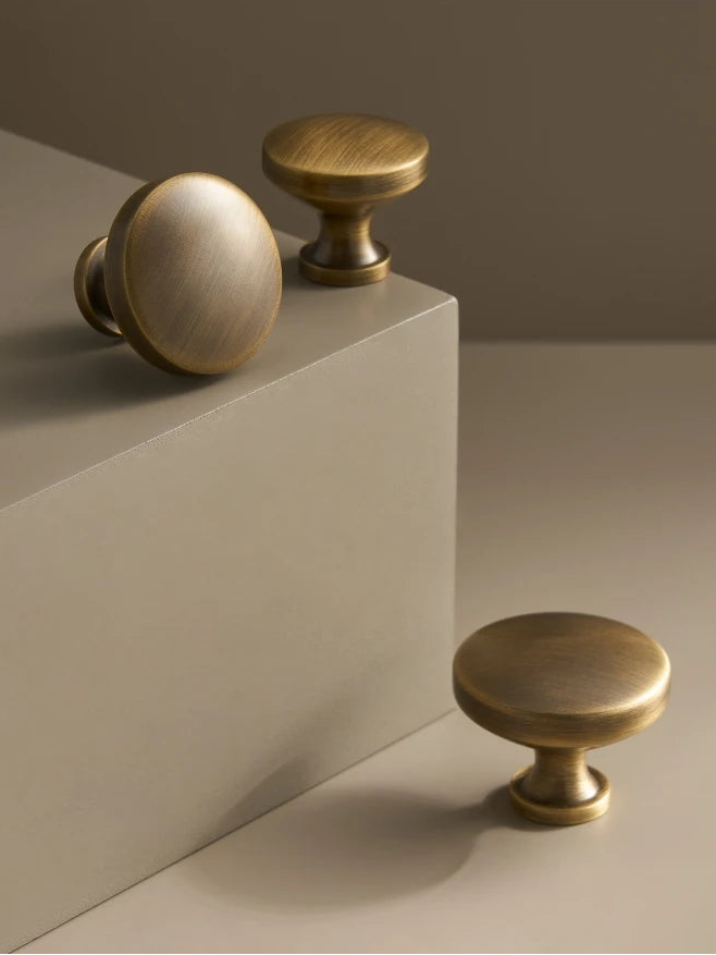 Three brass cabinet knobs on a neutral background .