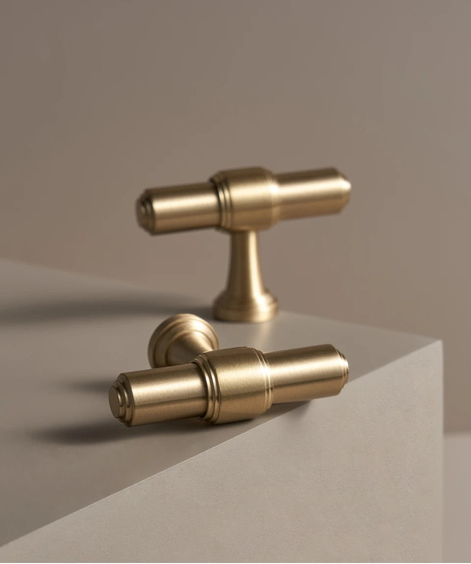 Two solid brass European luxury design gold knobs beige background.