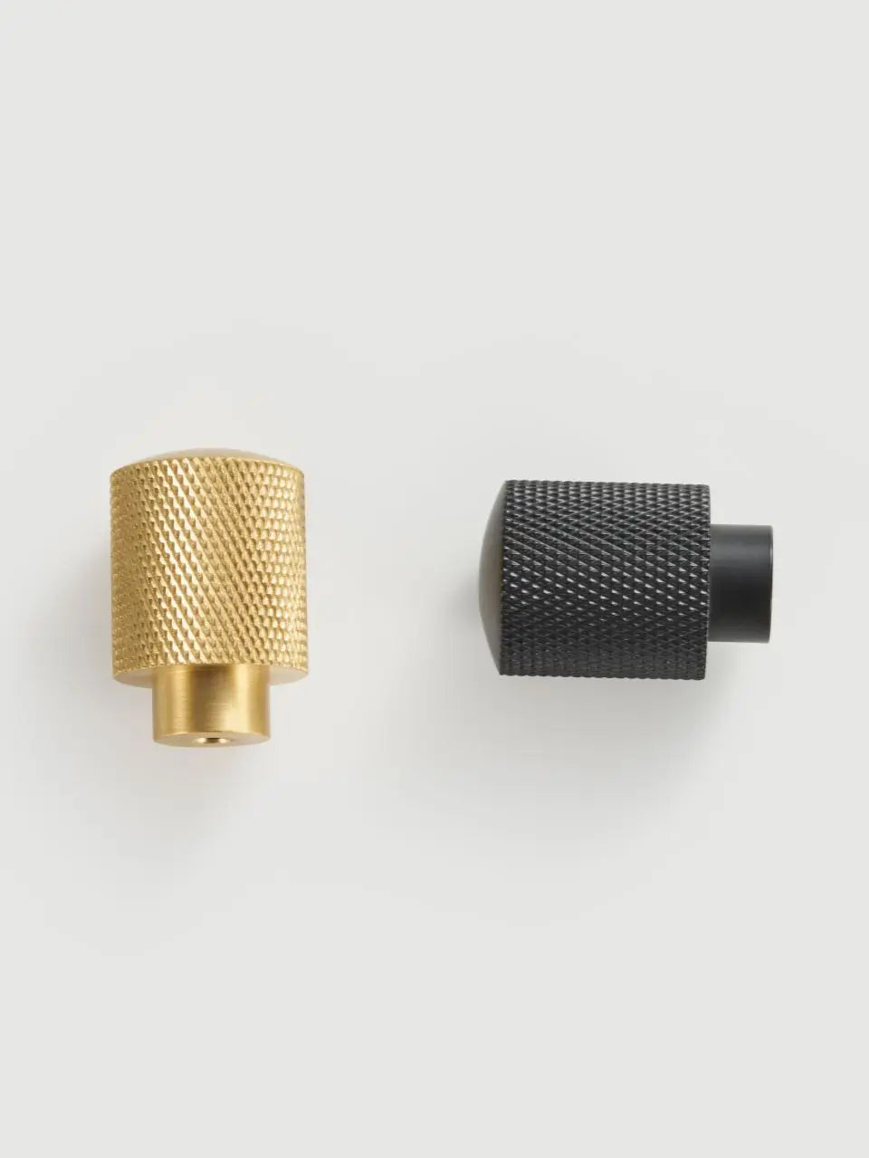 Two Gold and black cross knurled knobs on a white background.