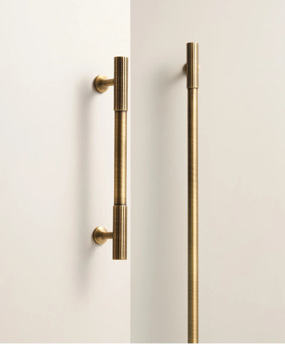 Pair of antique brass Art Deco handles on a white door.