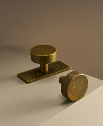 Two antique brass ice flower vintage door knobs on a beige background.