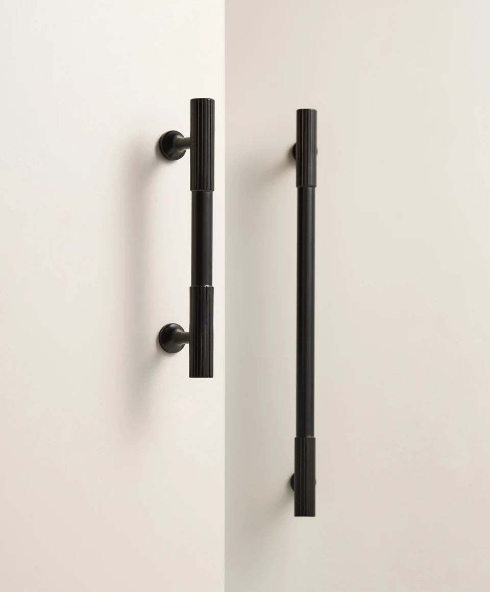 Pair of black brass Art Deco door handles on a white door.
