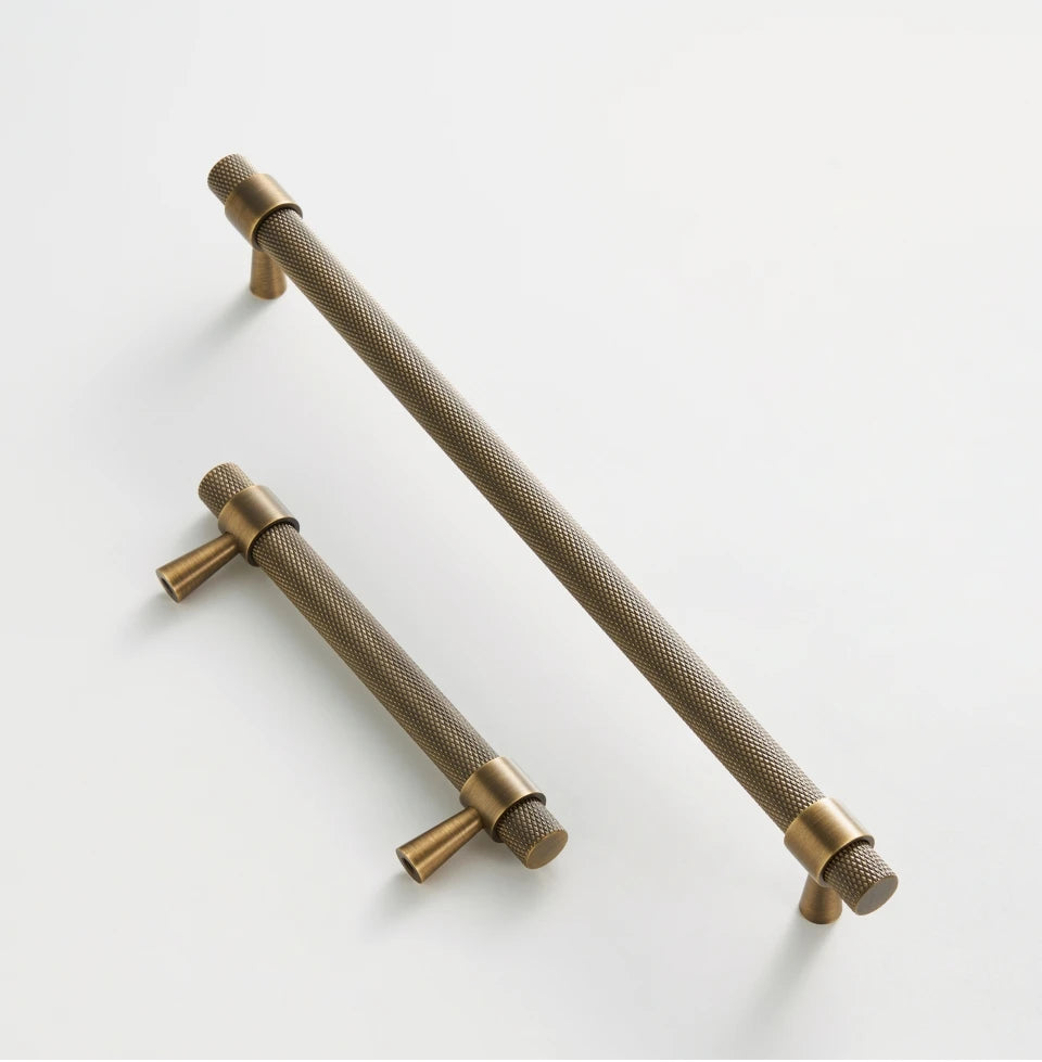 Two brass knurled cabinet handles on a white background.