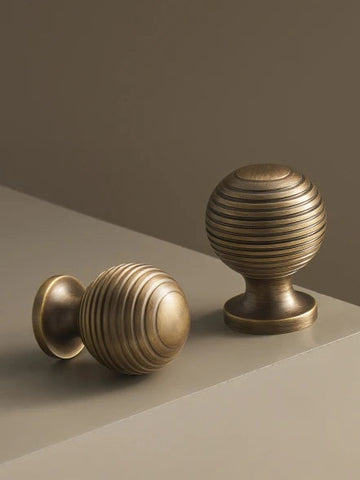 Two brass retro cabinet knobs on a neutral background.