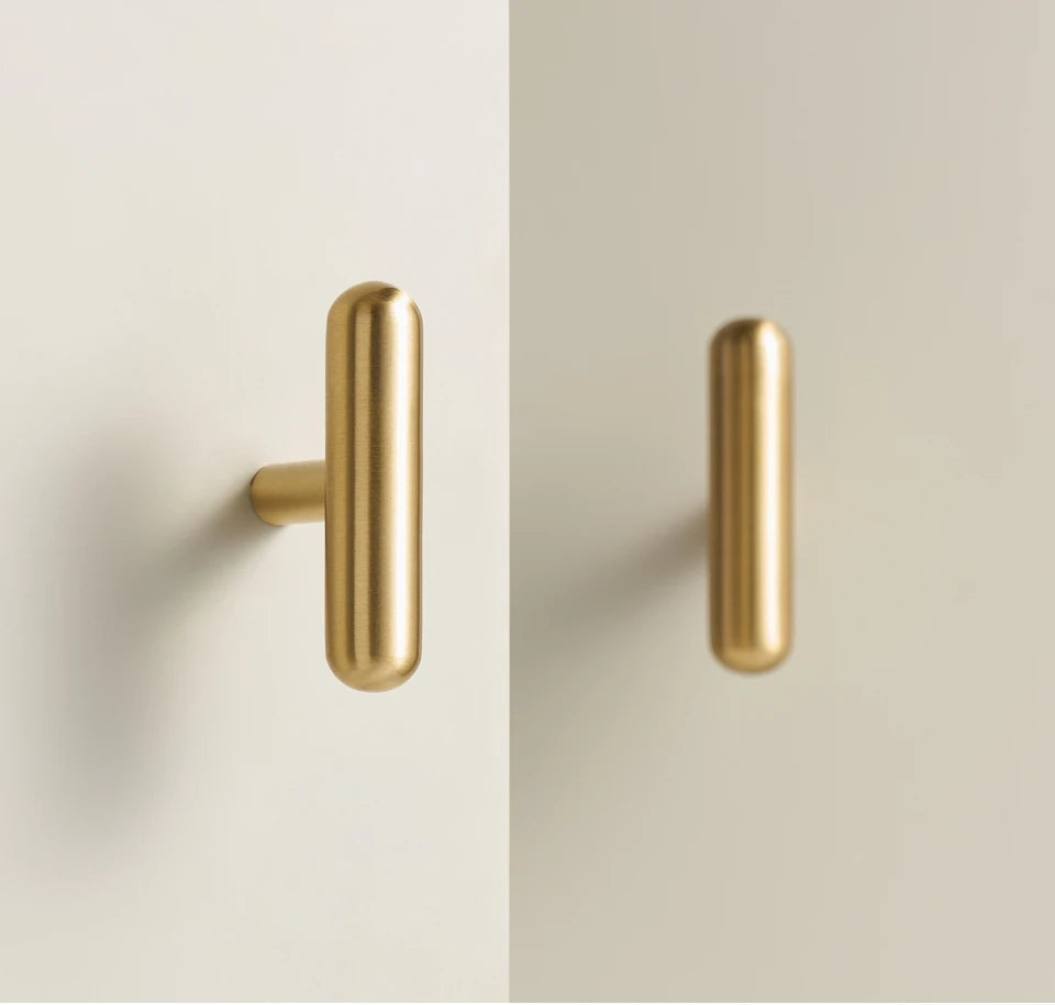 Two solid brass smooth gold cabinet round t-bars on a two-tone background.