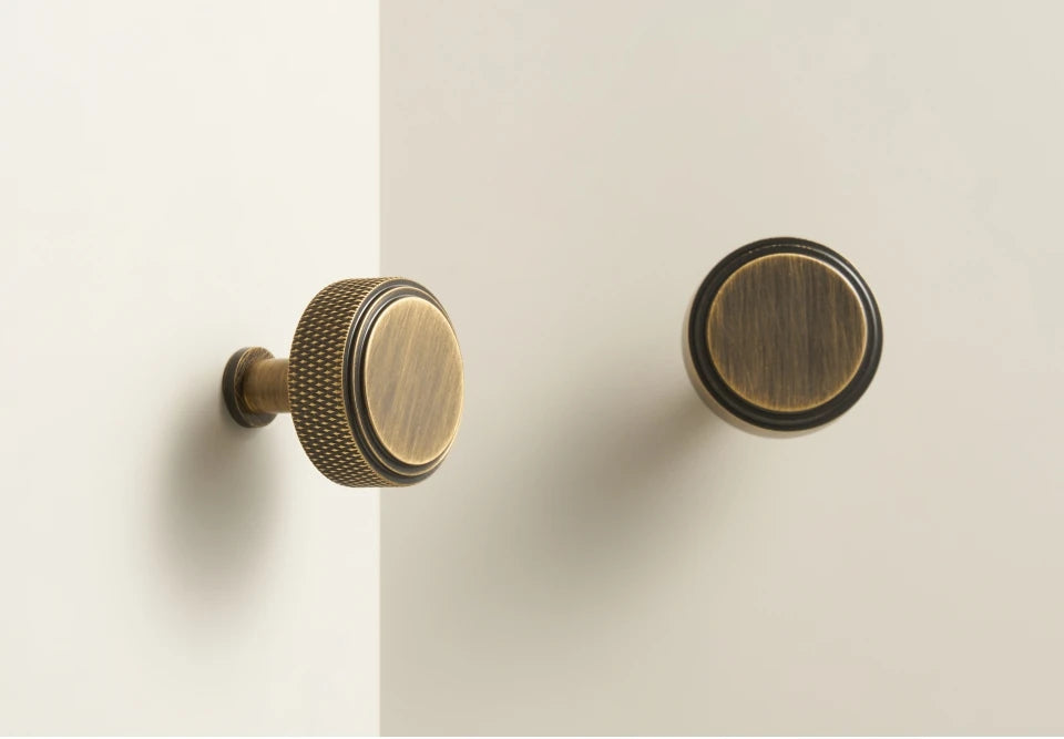 Two bronze diamond cabinet knobs on a beige background.