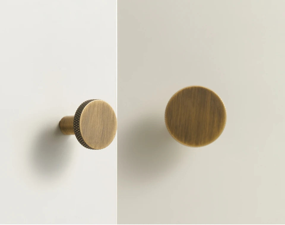 Two bronze matte antique cabinet knobs on a light grey background.