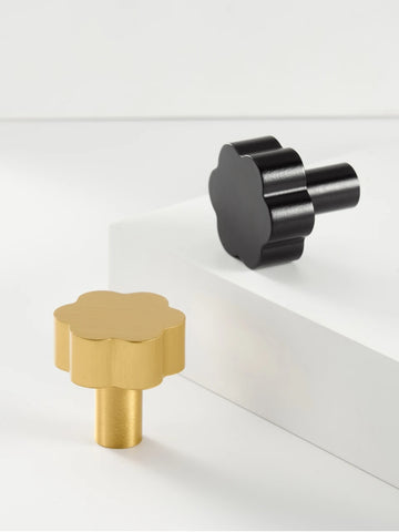 Two flower cabinet knobs in gold and black on a white surface.