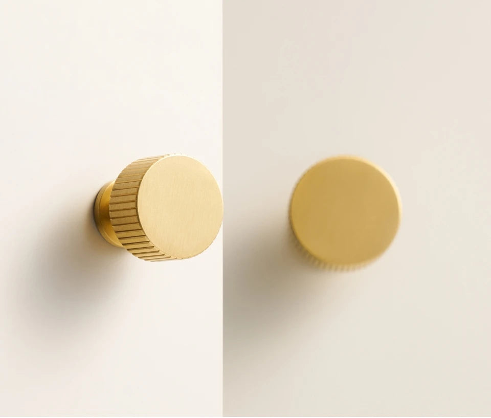 Two gold brass Art Deco knobs on a white background.