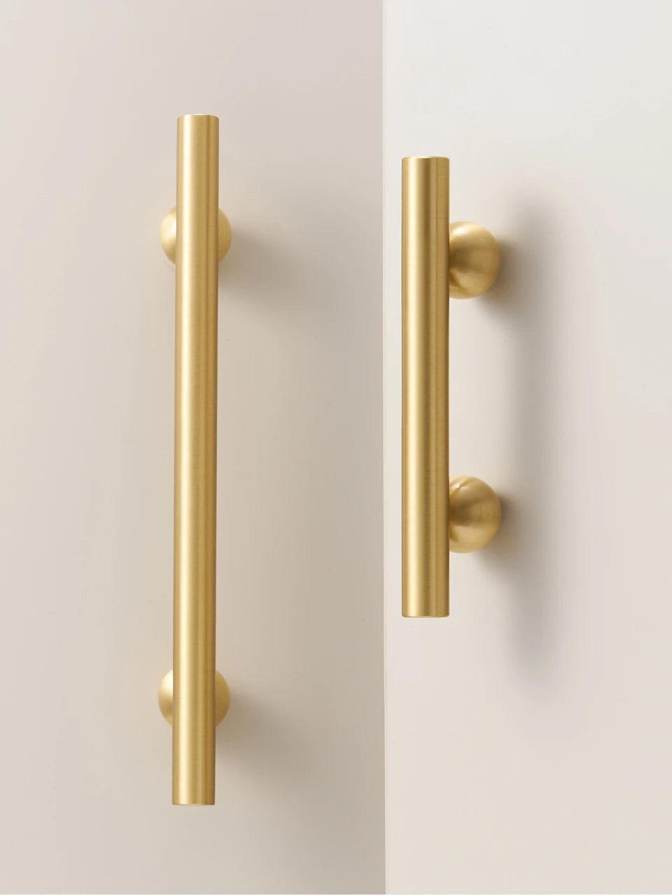 Two gold brass round ball handles on a white surface.