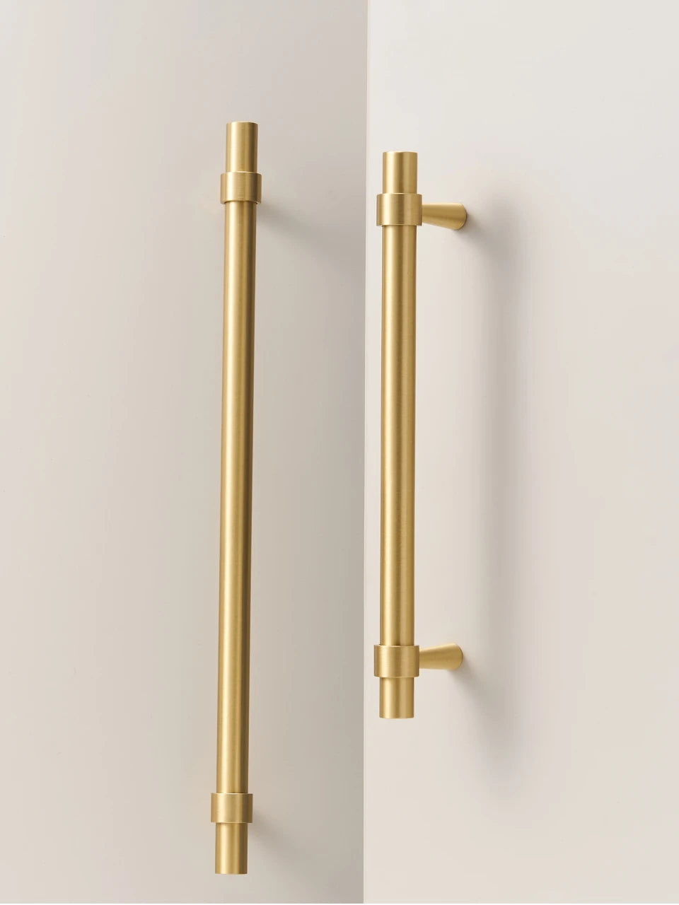 Two gold brass stepped ring handles on a light gray background.