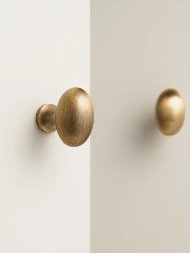 Two gold cabinet knobs on a white door.