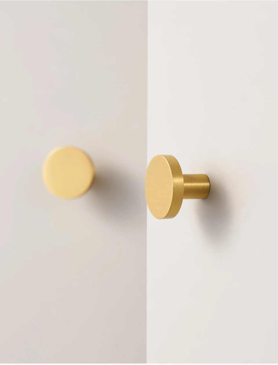 Two gold round cabinet knobs on a white background.