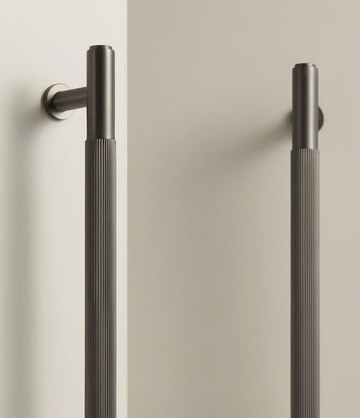 Pair of gunmetal brass linear handles on a white background