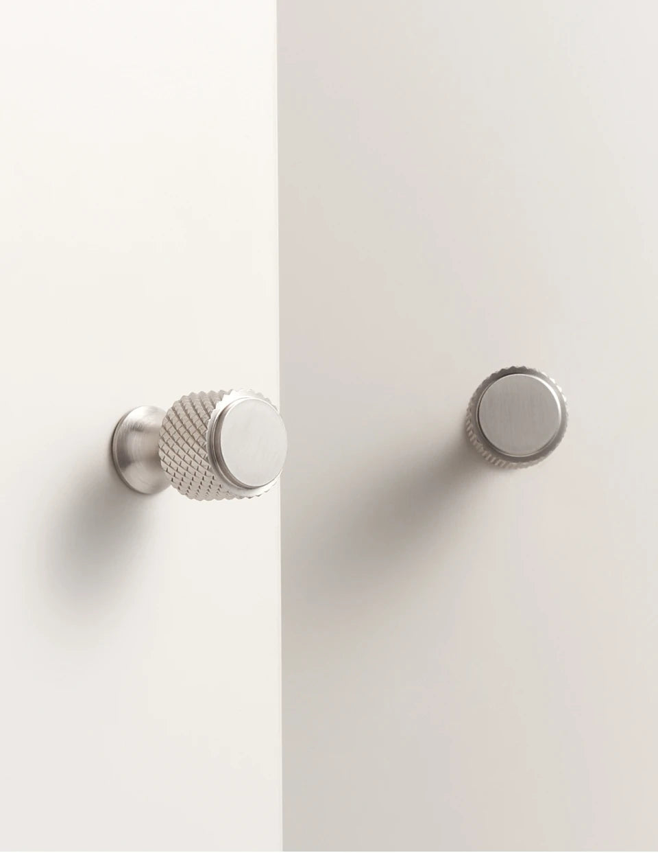 Two nickel cabinet knobs knurled on light grey background.