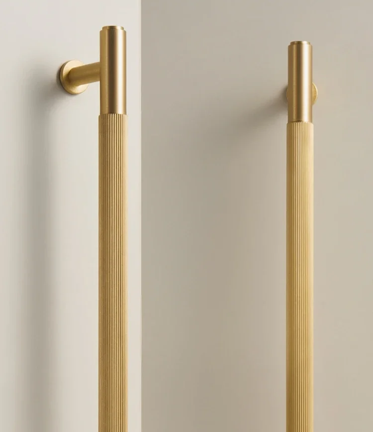 Two solid gold brass linear handles on a neutral background.