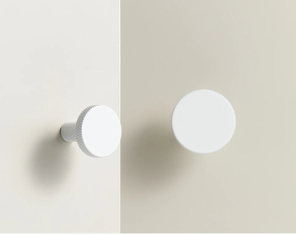 Two white matte antique cabinet knobs on a light grey background.