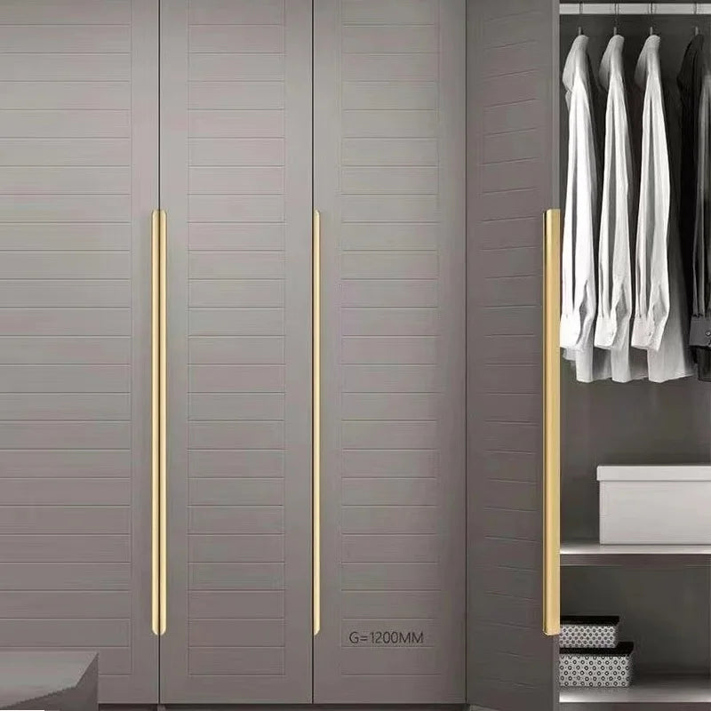 Modern wardrobe with gold aluminum edge pulls and hanging clothes in a room.