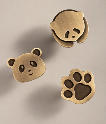 Three antique brass cabinet knob designs: smiling panda, resting panda and paw print