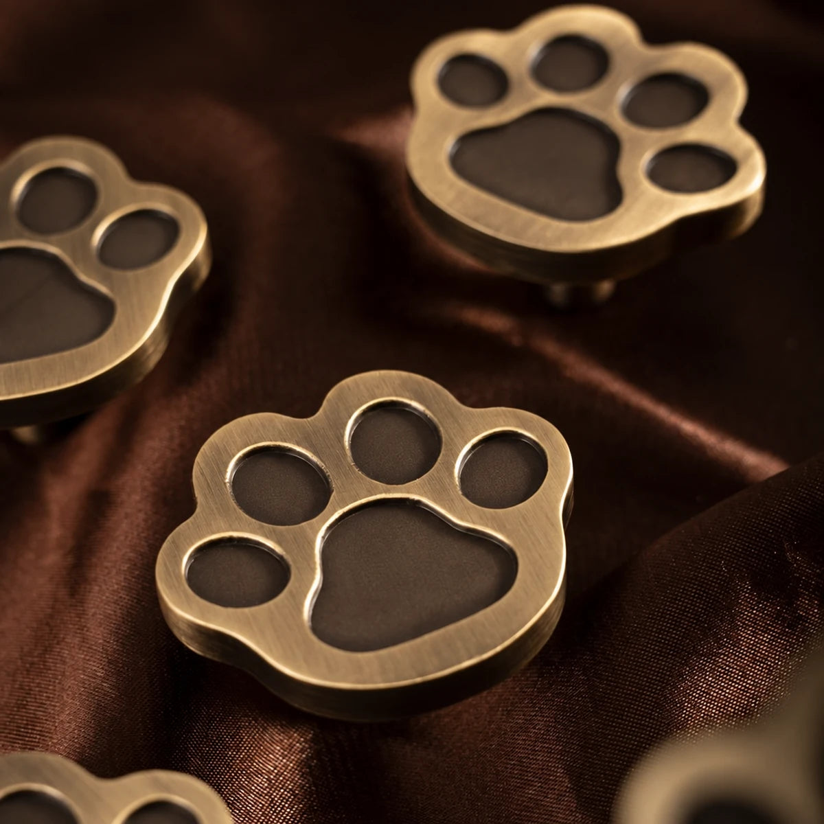Antique brass paw cabinet knobs with recessed toe and paw-pad details