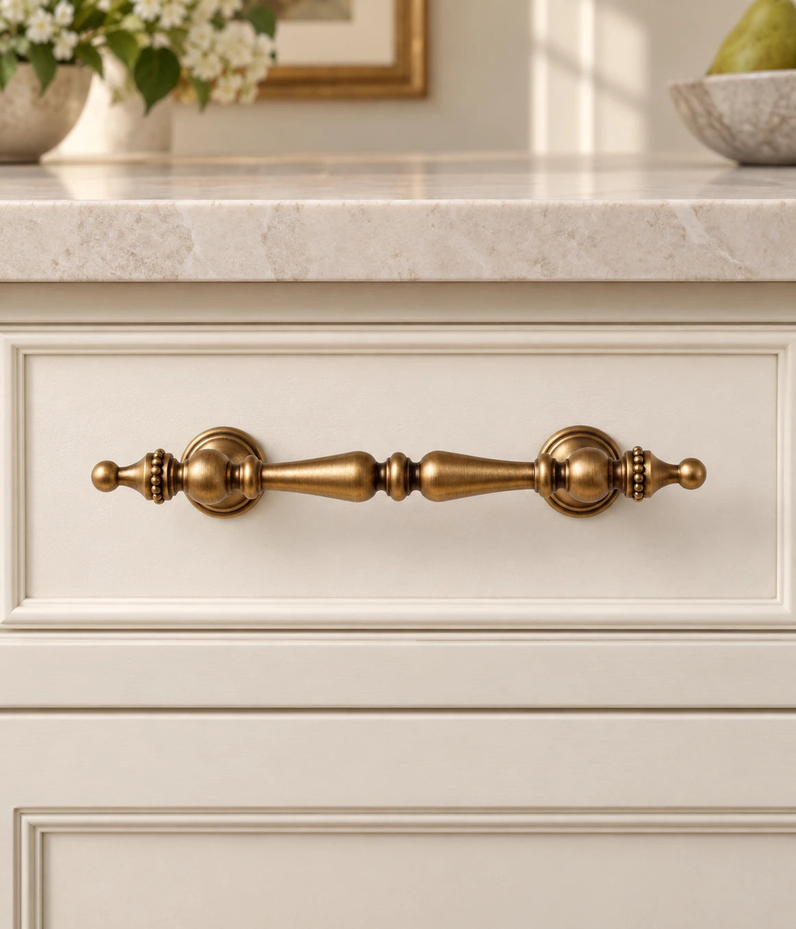 Antique brass crown finial cabinet pull installed on a cream drawer