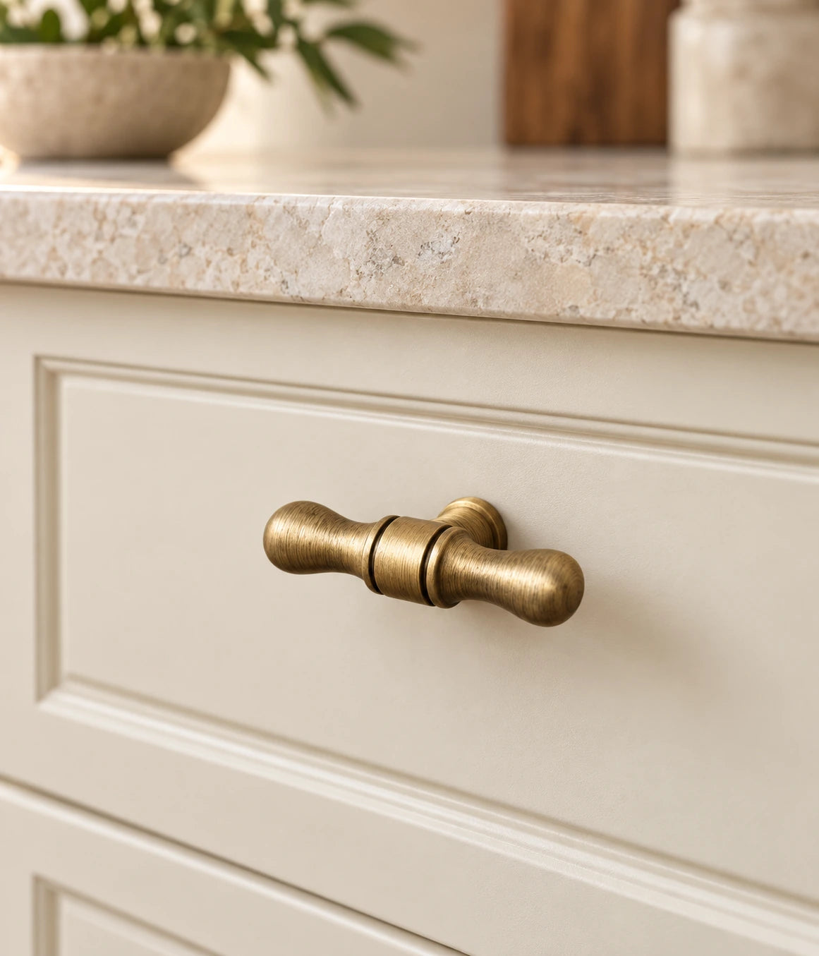 Antique brass turned-tip T-knob installed on a cream cabinet drawer