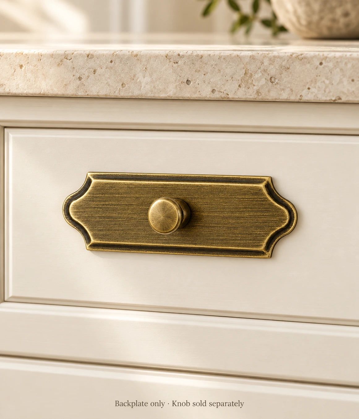 Antique brass scalloped cabinet knob backplate installed on a cream drawer; knob shown for illustration and sold separately