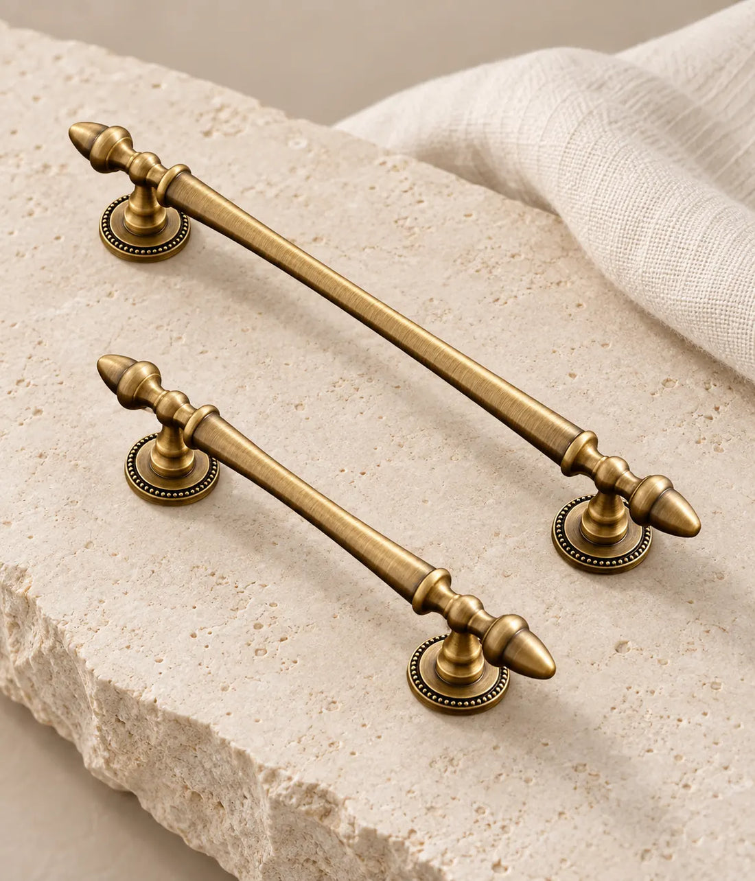 Antique brass acorn finial cabinet pulls with beaded bases arranged on pale limestone