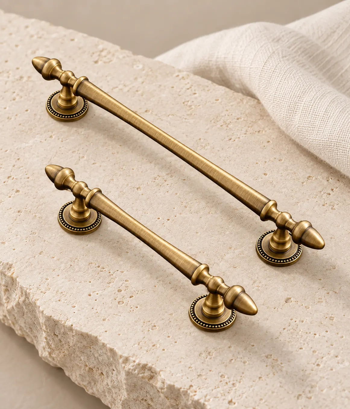 Antique brass acorn finial cabinet pulls with beaded bases arranged on pale limestone