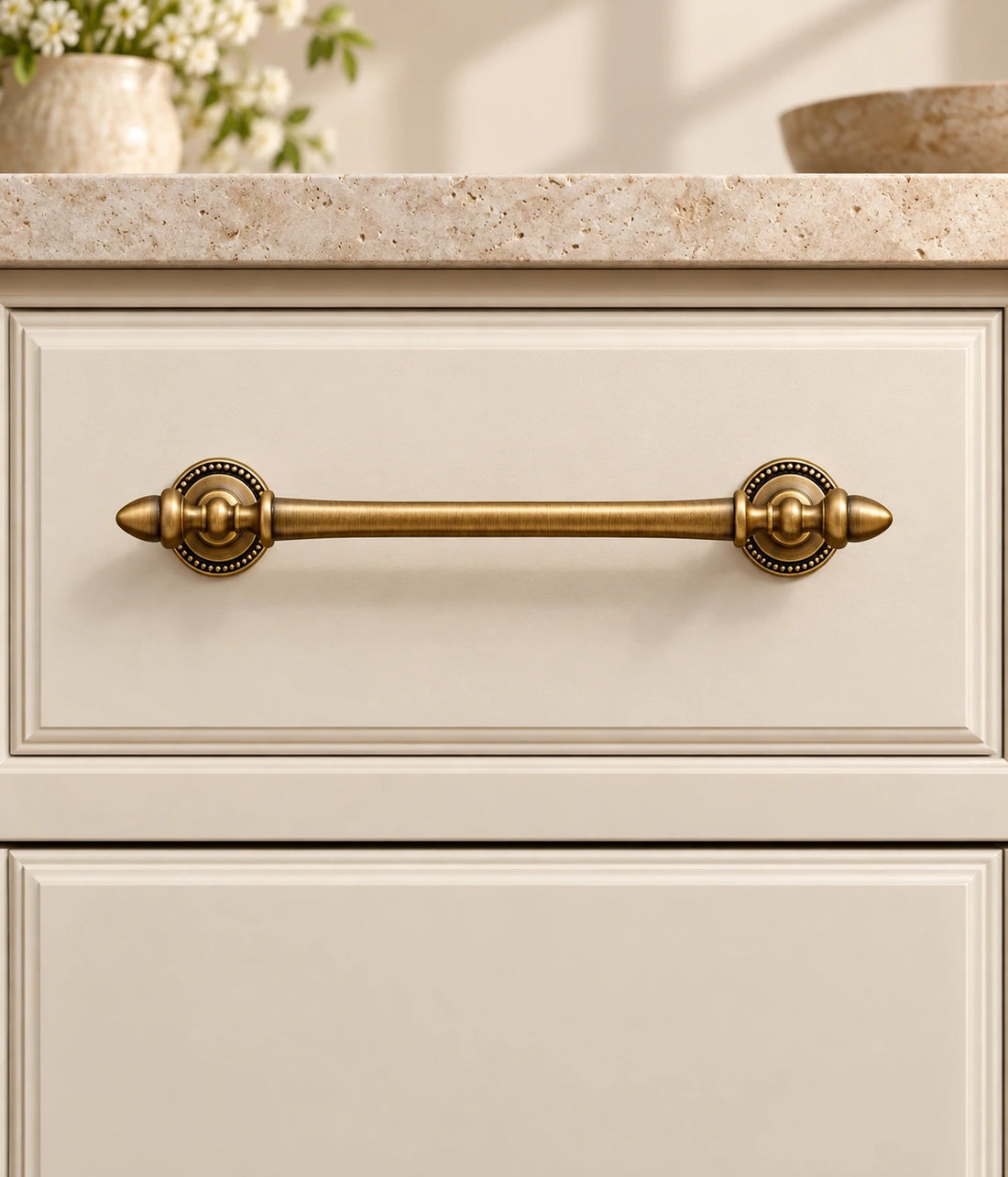 Antique brass acorn finial cabinet pulls with beaded bases arranged on pale limestone