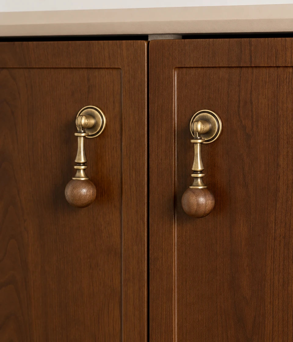 Turned antique brass drop pulls with walnut balls installed on wood cabinet doors