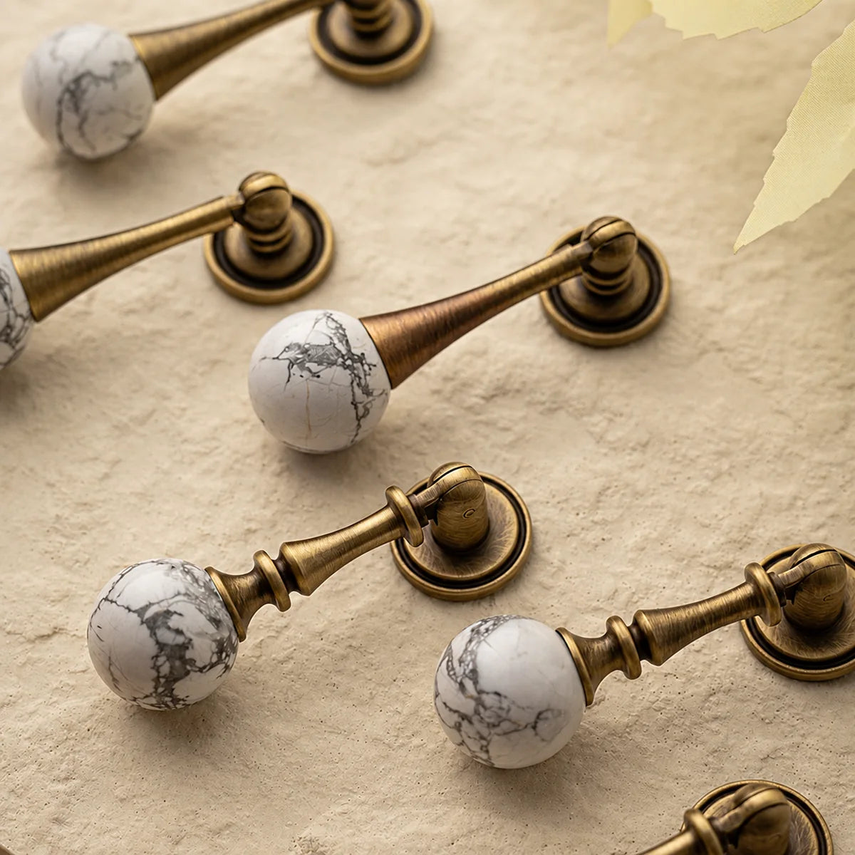 White veined stone ball drop pulls with tapered and turned antique brass stems
