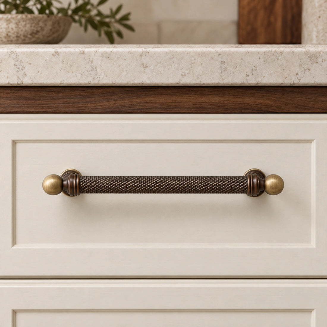 Dark and golden antique brass ball-end knurled cabinet pulls on limestone