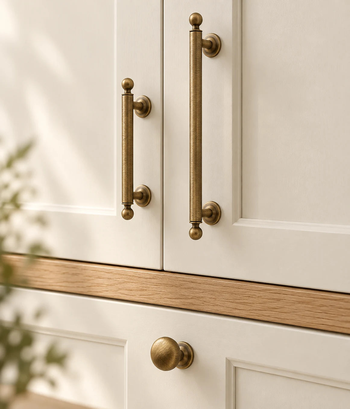 Antique brass ball-finial pulls and round knob on warm cream cabinet fronts
